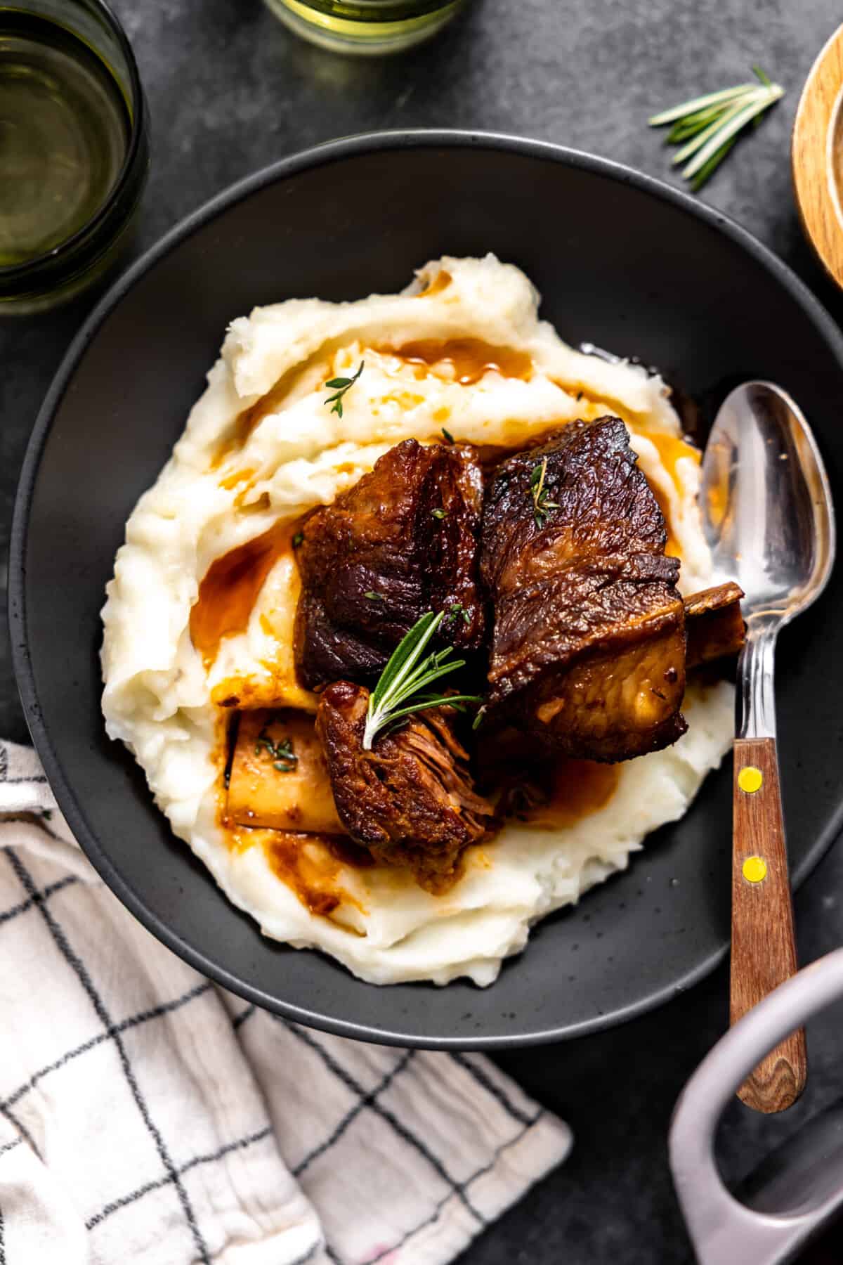 Short ribs served over mashed potatoes on a plate.