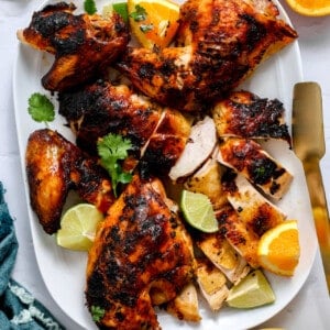 Plate of pollo asado served with tortillas on the side.