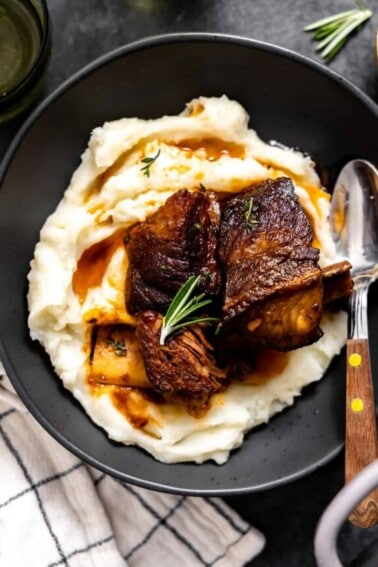 Short ribs served over mashed potatoes on a plate.