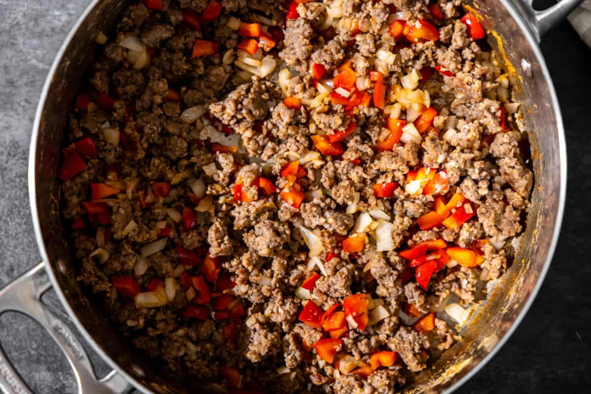 Ground sausage, onion, and bell pepper cooking in a skillet. 