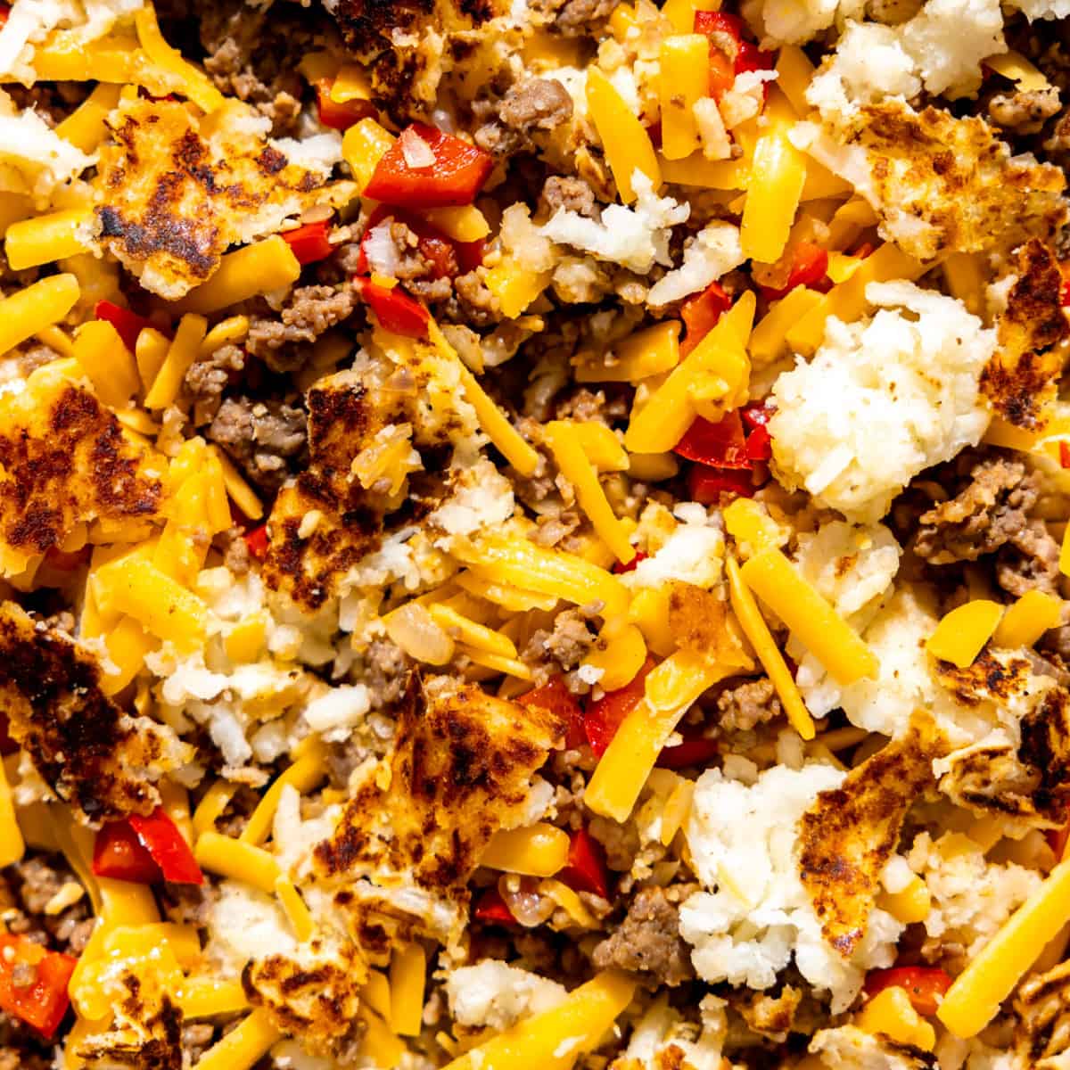 Hasbrowns, ground sausage, bell peppers and cheese in a baking dish. 