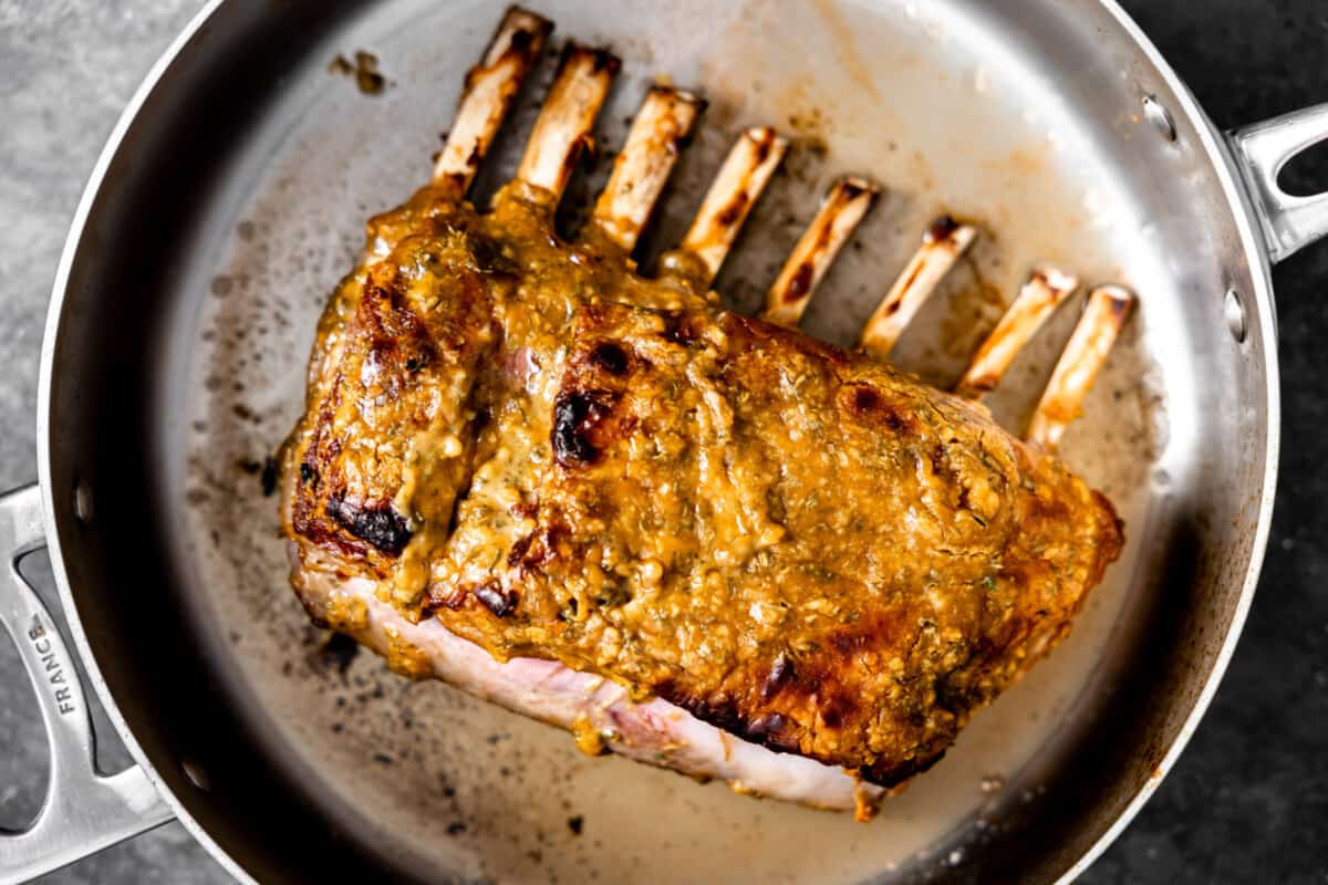 Rack of lamb searing in a large skillet. 