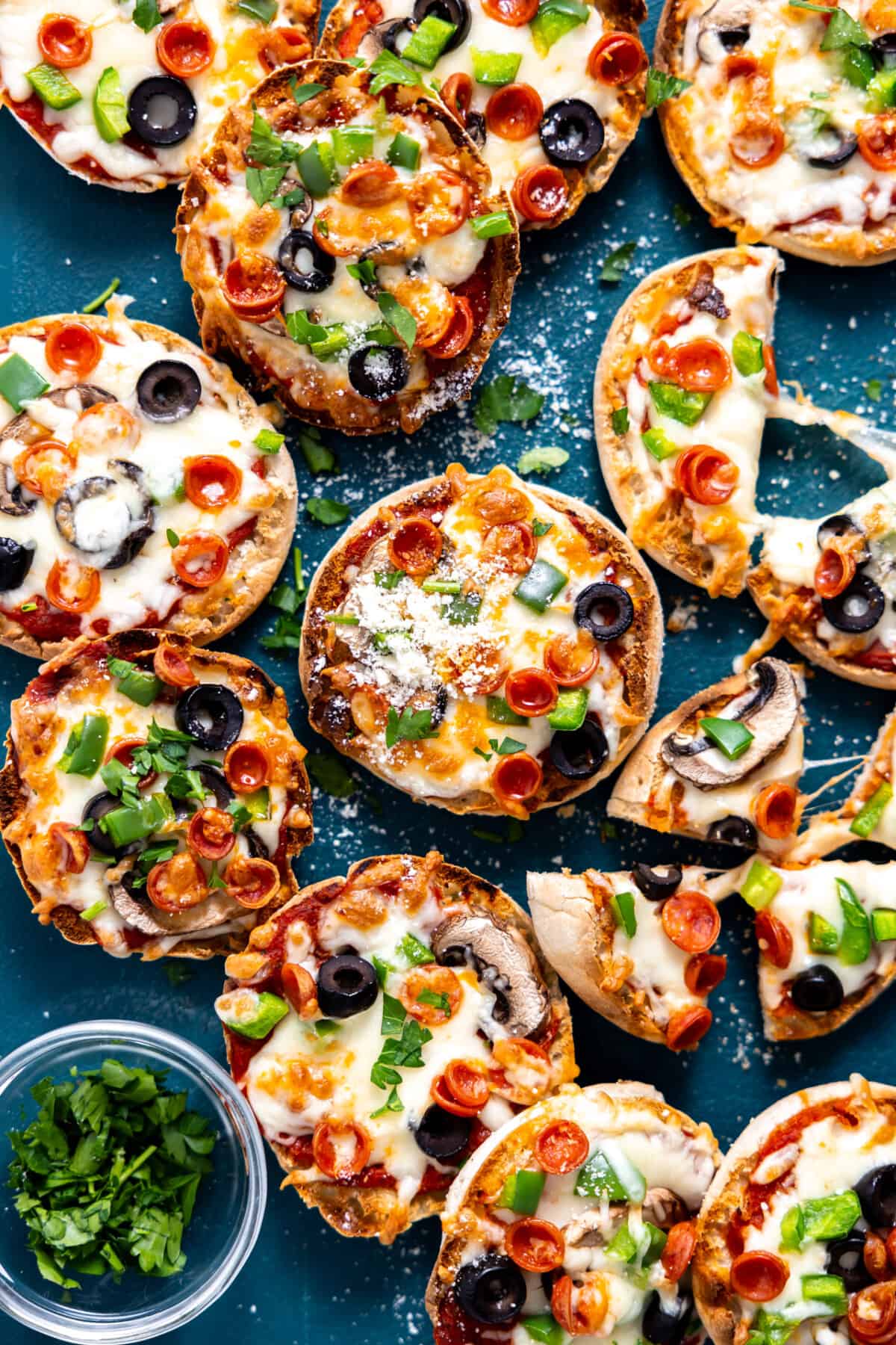 Tray of English Muffin Pizzas topped with pepperoni, bell pepper, olives and mushrooms.