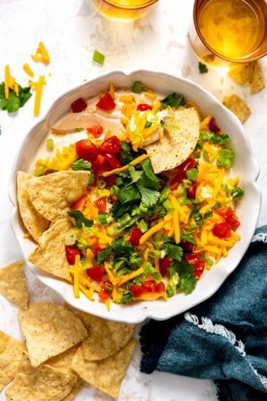 Taco dip in a white dish served with tortilla chips.