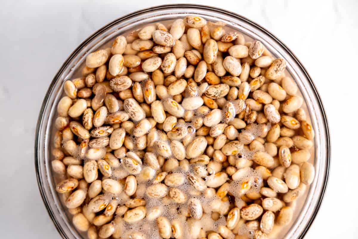 Pinto beans soaking in a bowl of water.