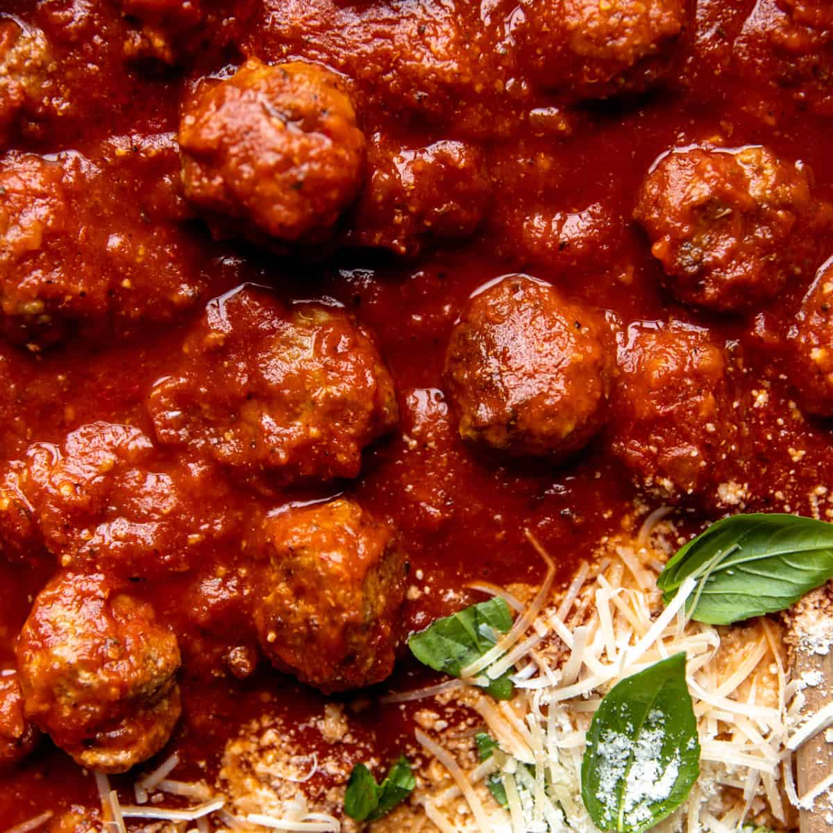 Meatballs in marinara sauce with parmesan on top.