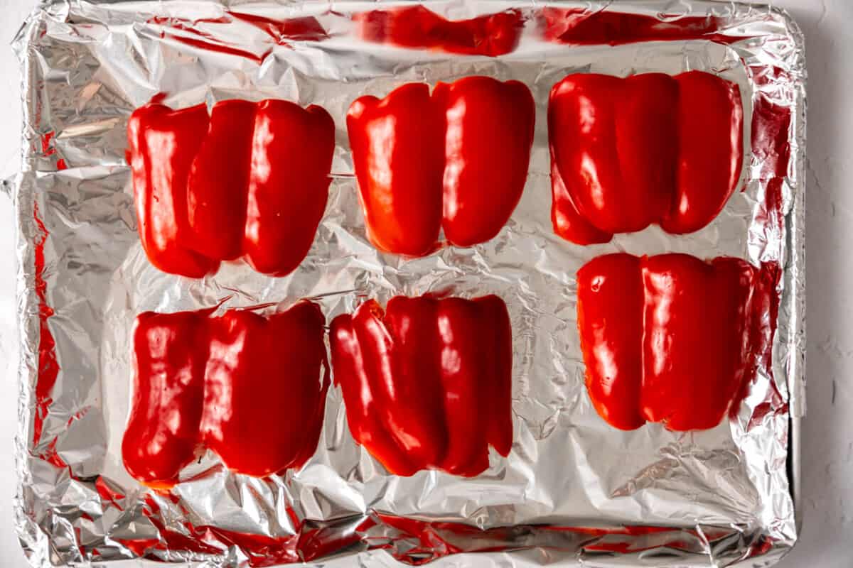 Red peppers sliced and on a baking sheet to roast.