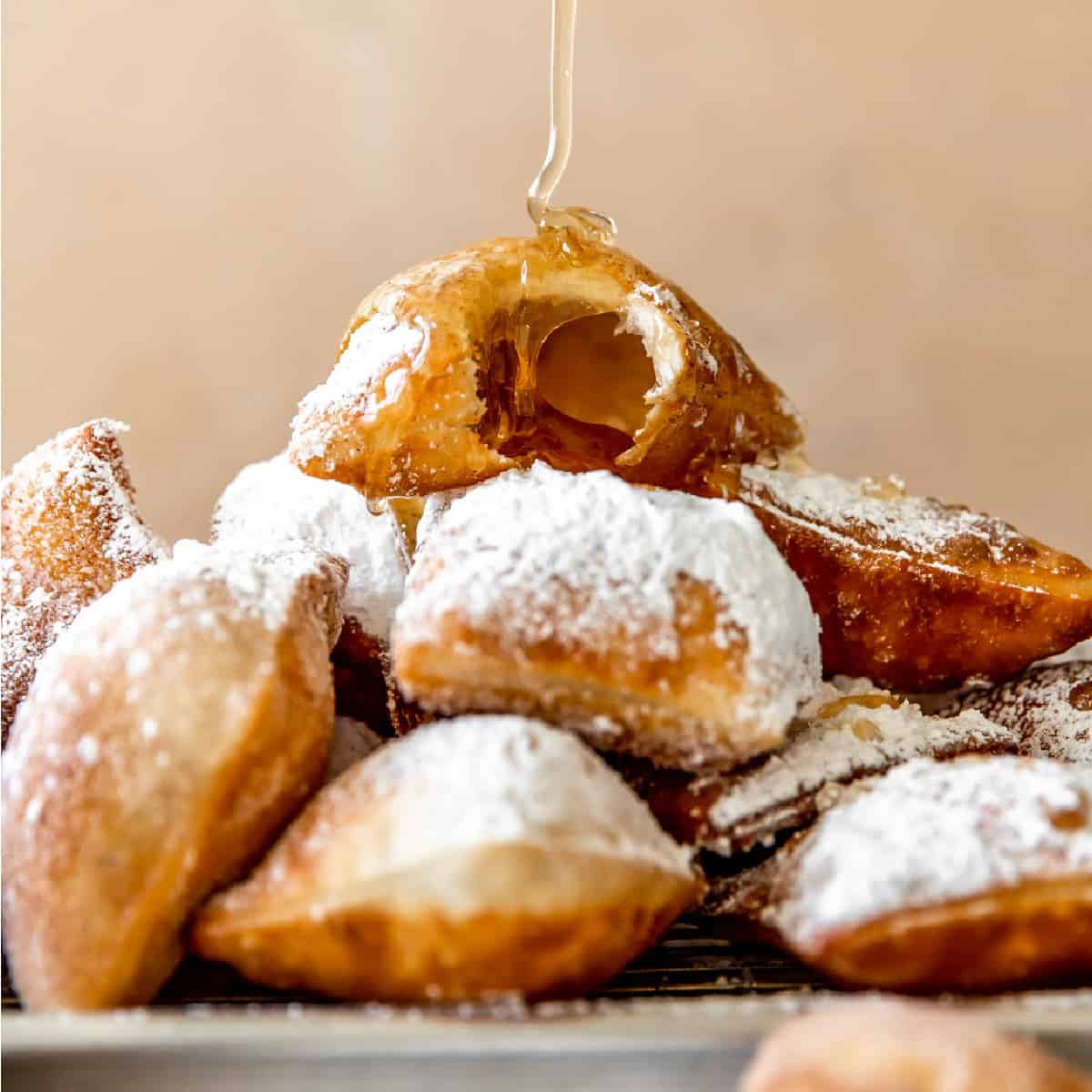 Stack of sopapillas being drizzled with honey.