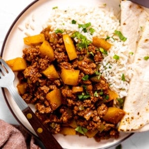 Plate with rice and ground beef picadillo with a flour tortilla.
