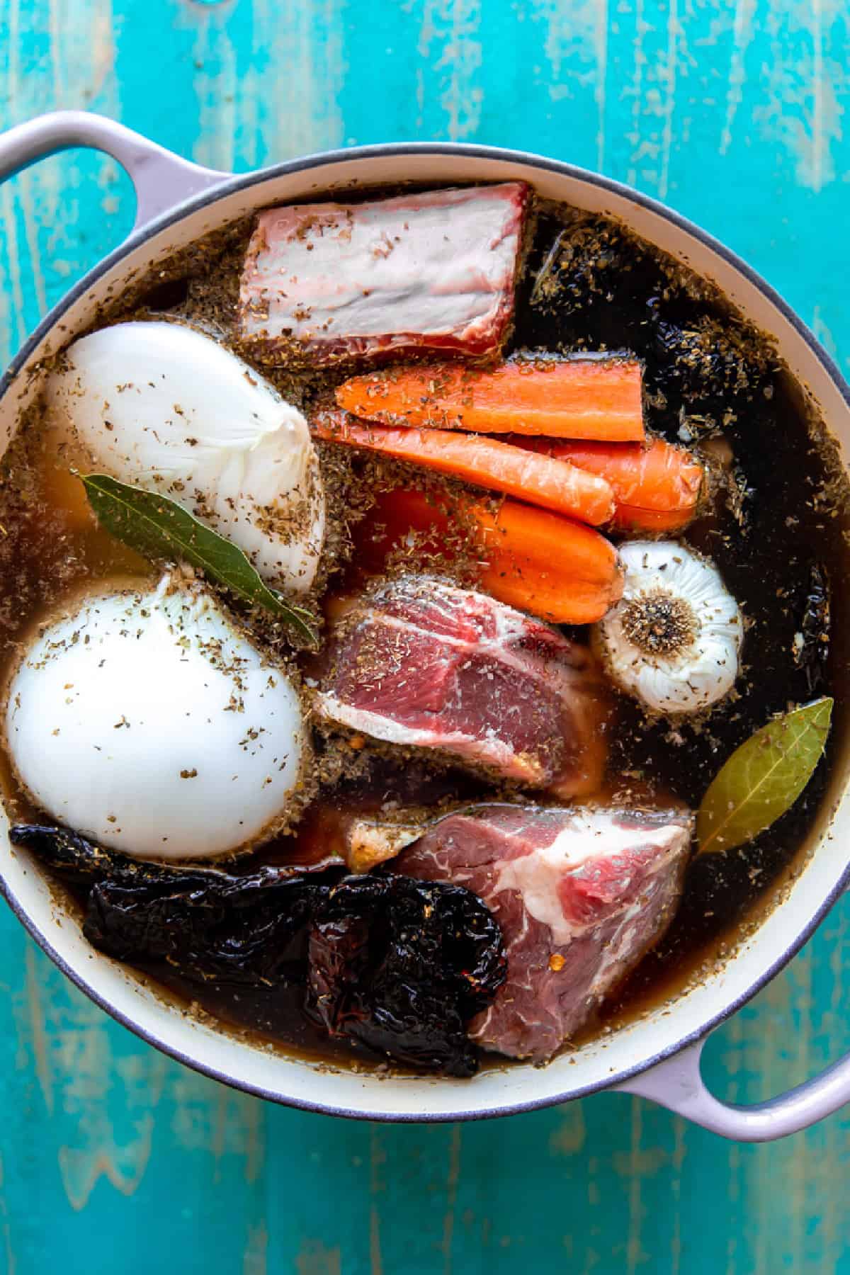 Stockpot with birria ingredients topped with water and seasonings ready to simmer.