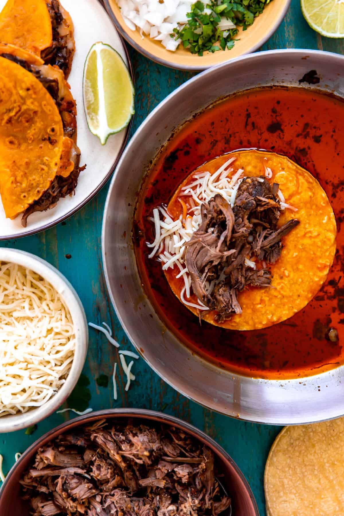 Making Birria Tacos with tortillas frying in red Chile oil and shredded meat with melty cheese inside. 