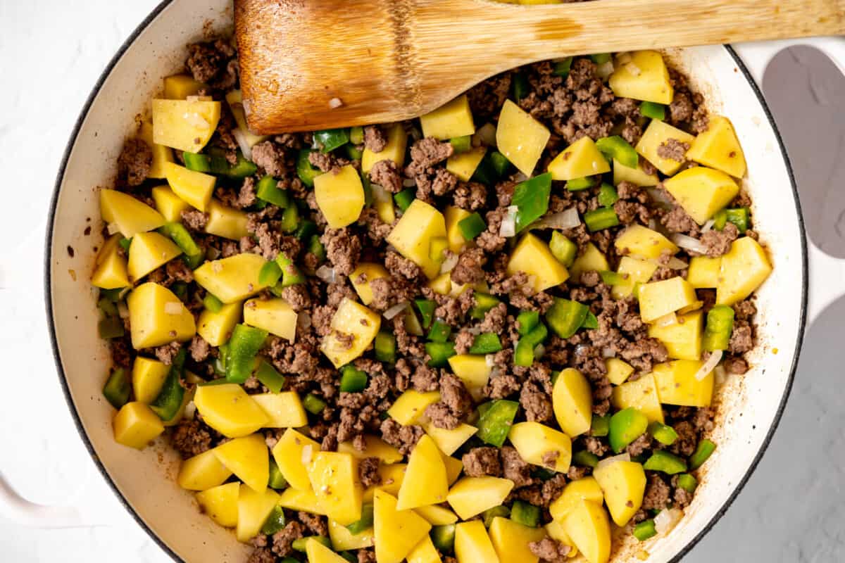 Ground beef and potatoes cooking in a skillet. 