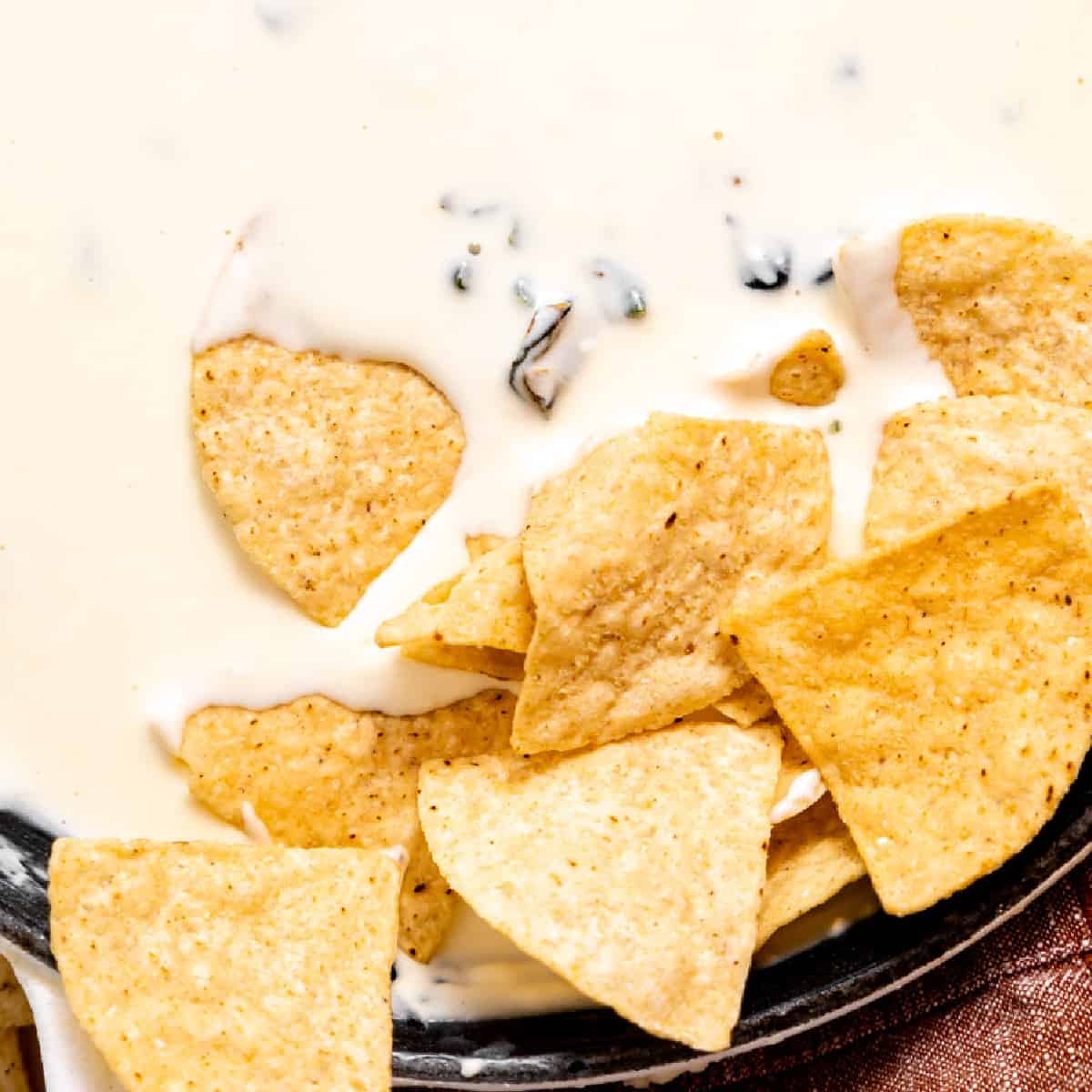 Chips dipped into white queso 