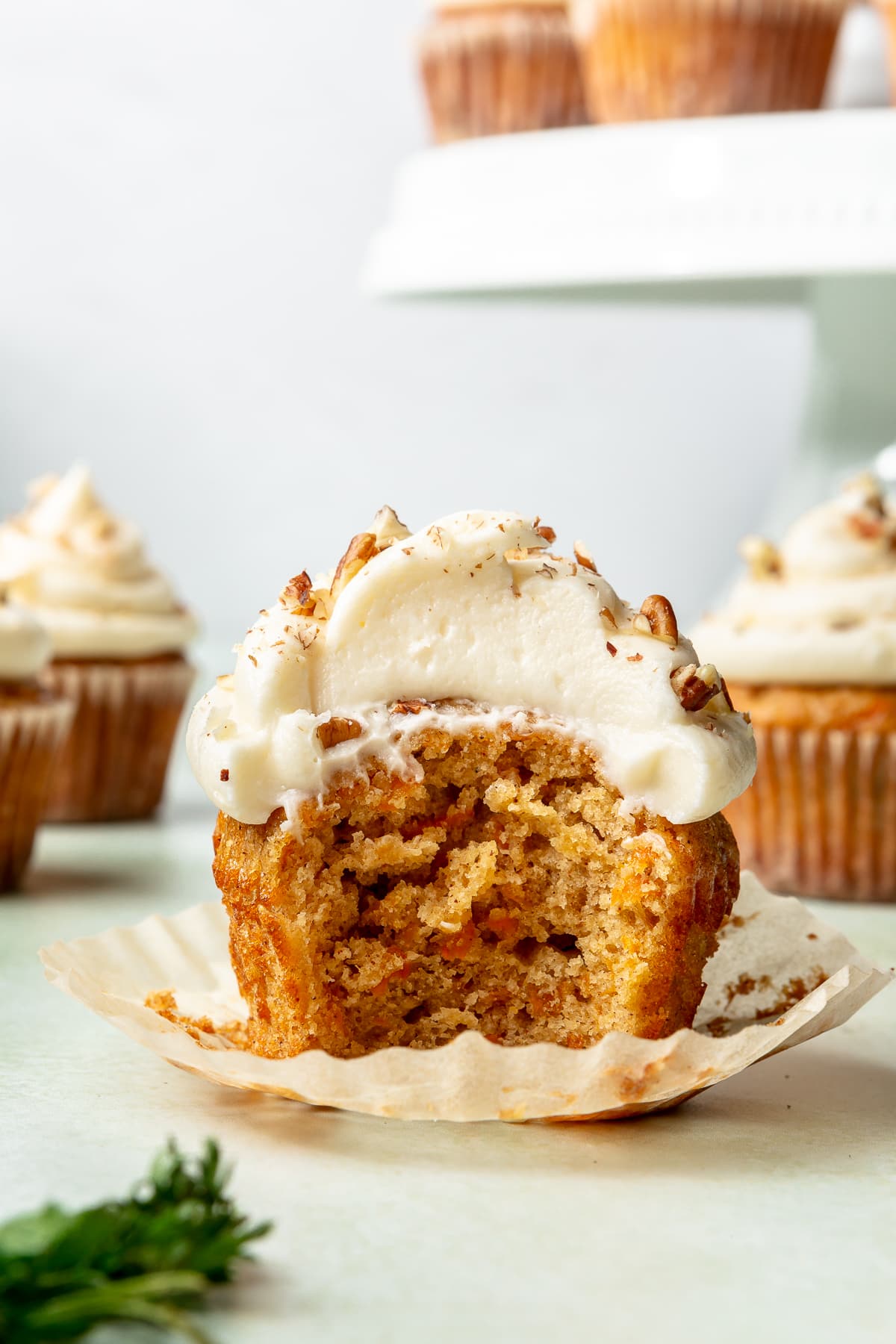Carrot cake cupcake with the wrapped down and a bite missing.