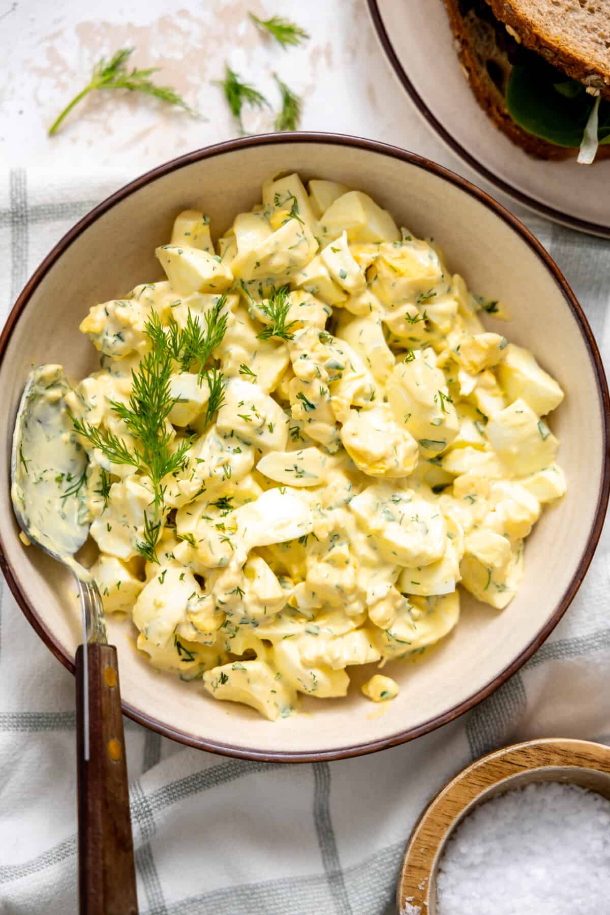 Bowl of egg salad topped with fresh herbs.