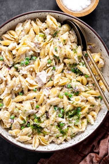 Bowl of tuna pasta salad with spoons for serving.