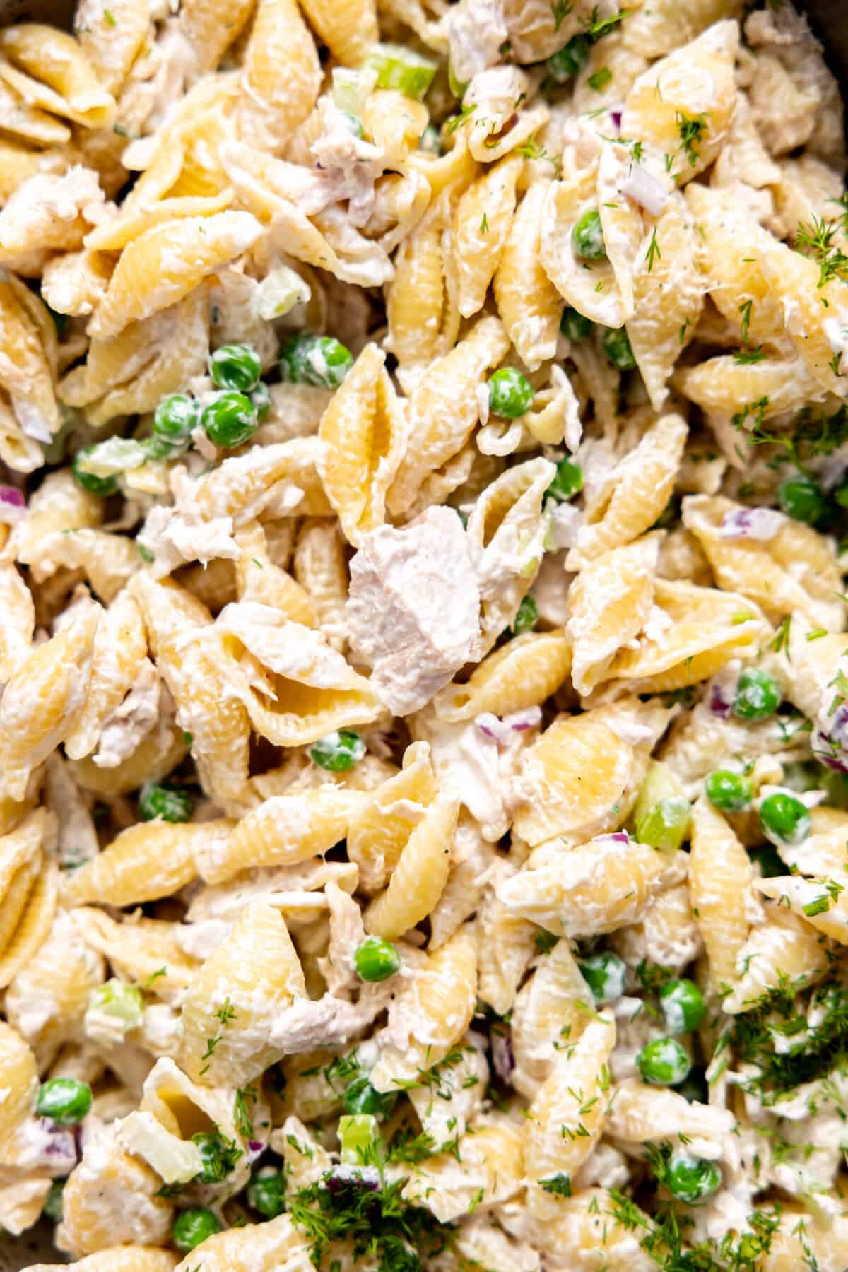 Up close of tuna pasta salad made with green peas, fresh dill, and a creamy dressing.