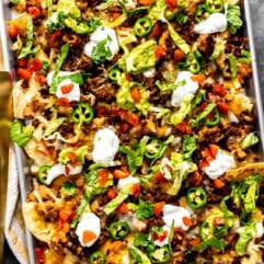 Sheet pan nachos with ground beef topped with sour cream and guacamole.
