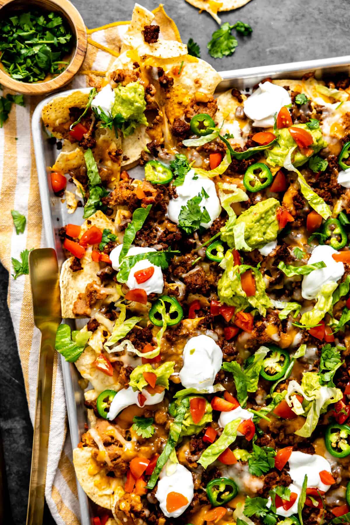 Sheet pan filled with nachos and toppings. 