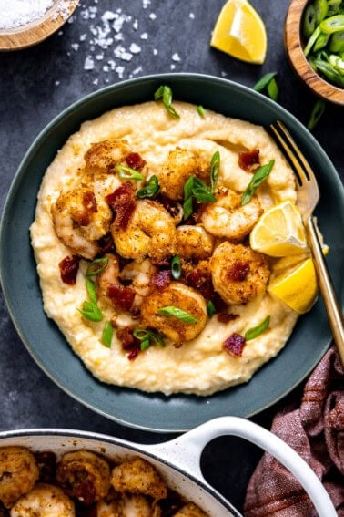 Bowl of shrimp and grits topped with parsley and a lemon wedge.