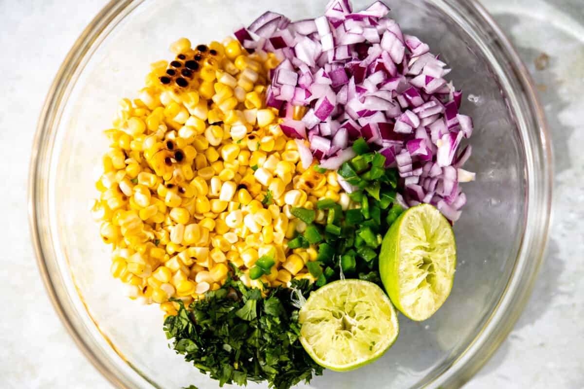 Ingredients for roasted corn salsa in a glass bowl.