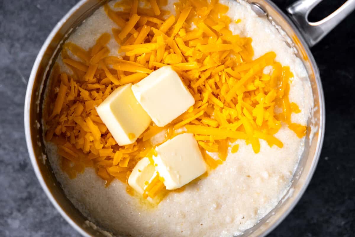 Saucepan with grits topped with grated cheese and butter. 