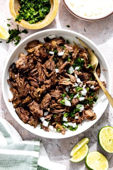 Bowl of barbacoa topped with cilantro and onion.
