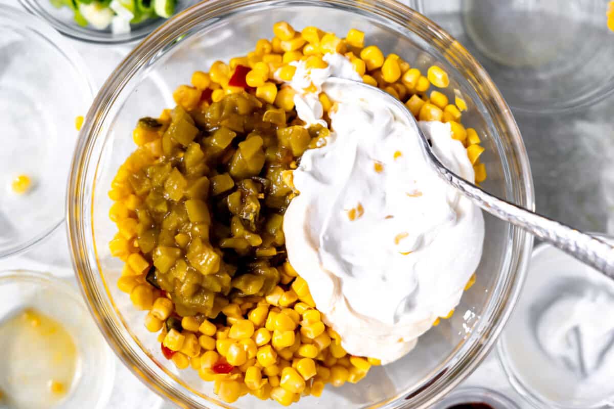 Glass bowl with corn, diced green chiles, mayonnaise and sour cream to make dip.