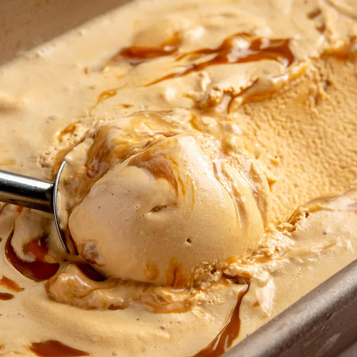 Ice cream scoop spooning up Dulce de leche ice cream with caramel drizzle.