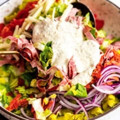 Grinder salad in a bowl with dressing added on top.