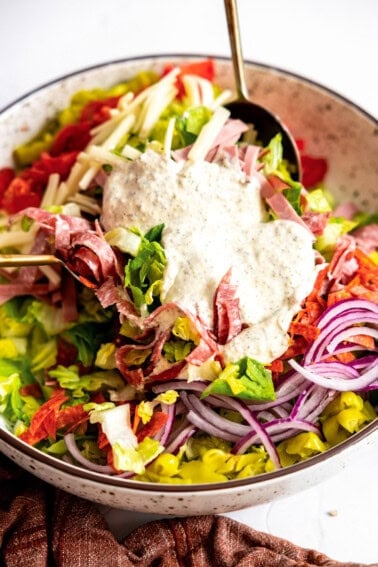 Grinder salad in a bowl with dressing added on top.