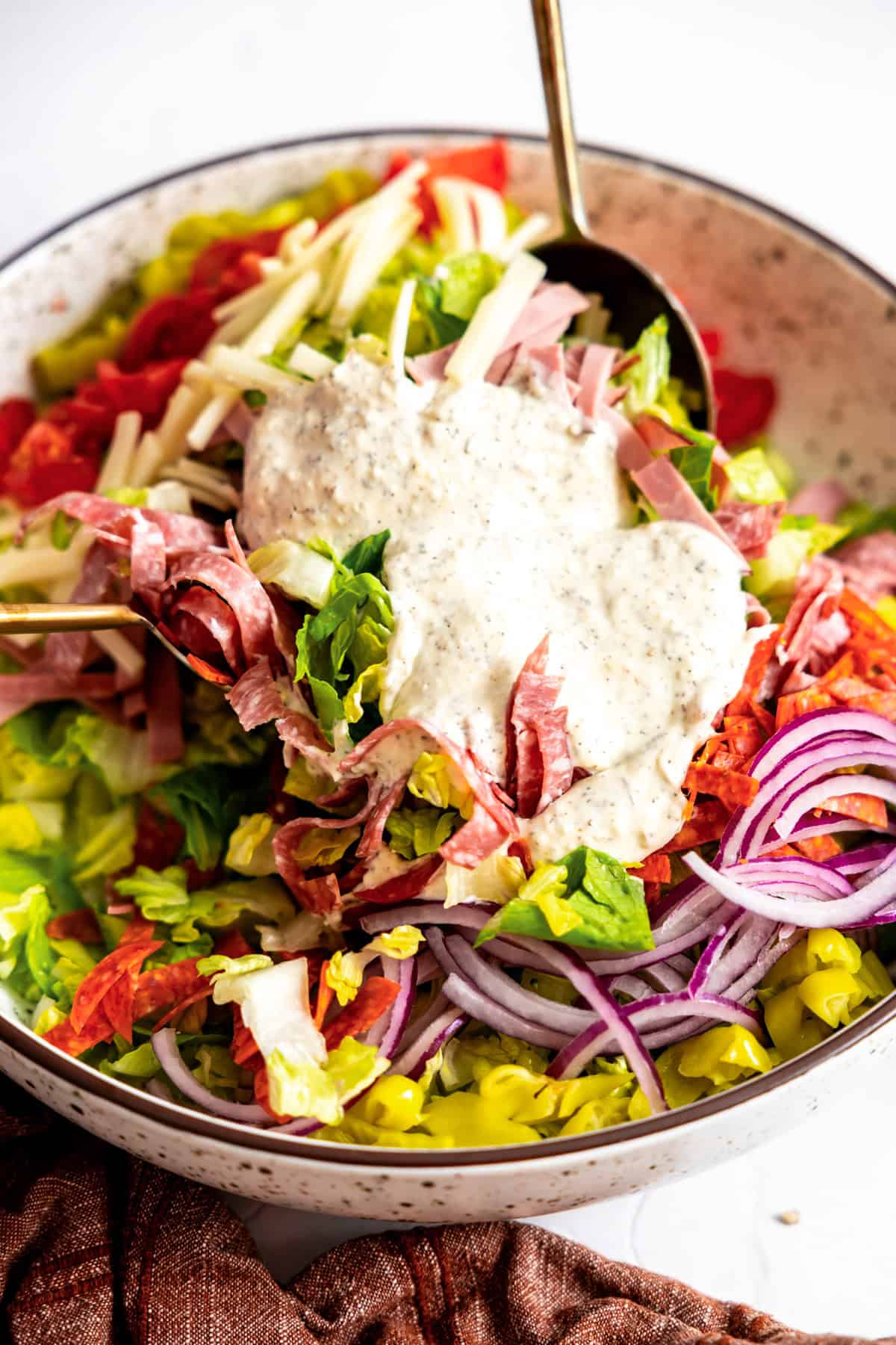 Grinder salad in a bowl with dressing added on top. 