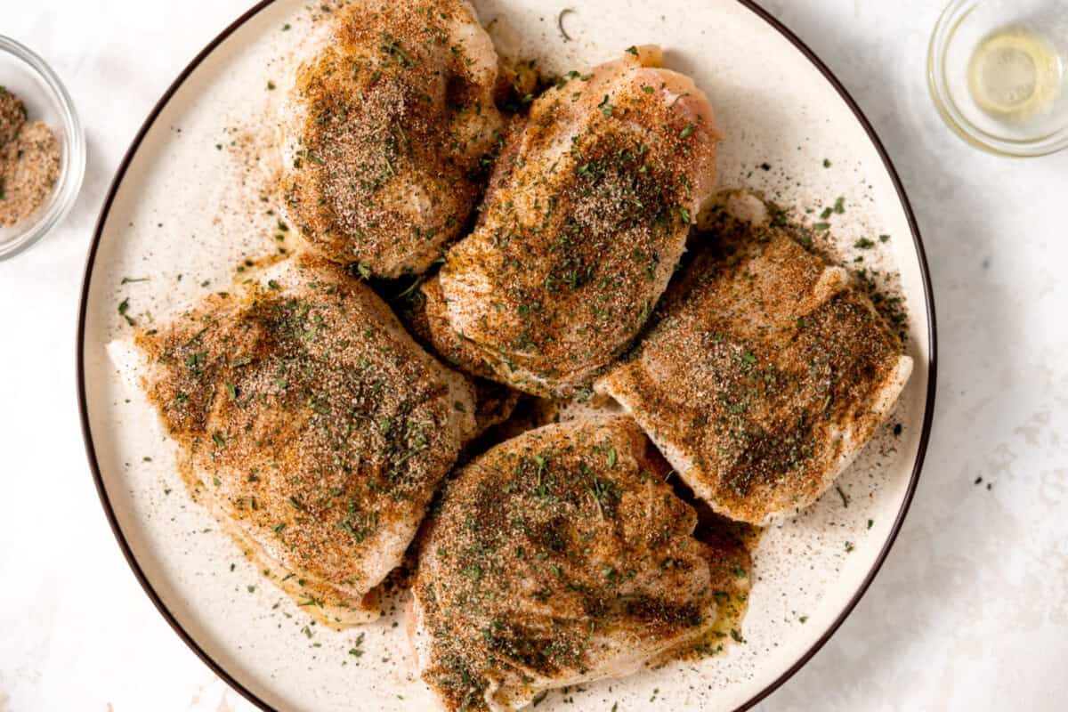 Seasoned chicken thighs on a plate. 