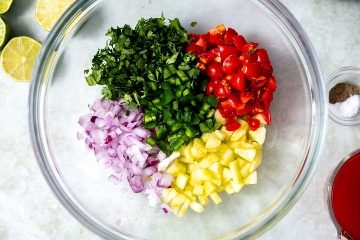 Diced cilantro, cucumber, red onion, jalapeño, red bell pepper in a bowl. 