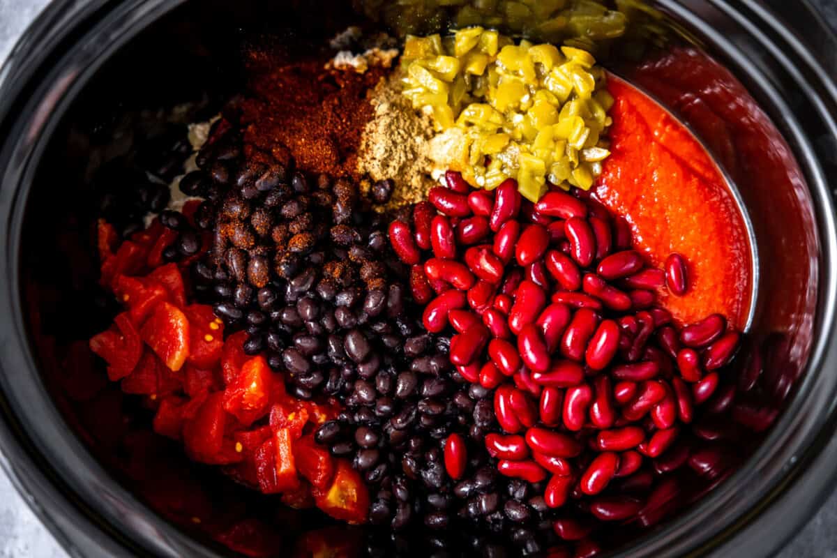 Adding cooked turkey, tomatoes, diced green chiles, beans, and spices to a slow cooker. 