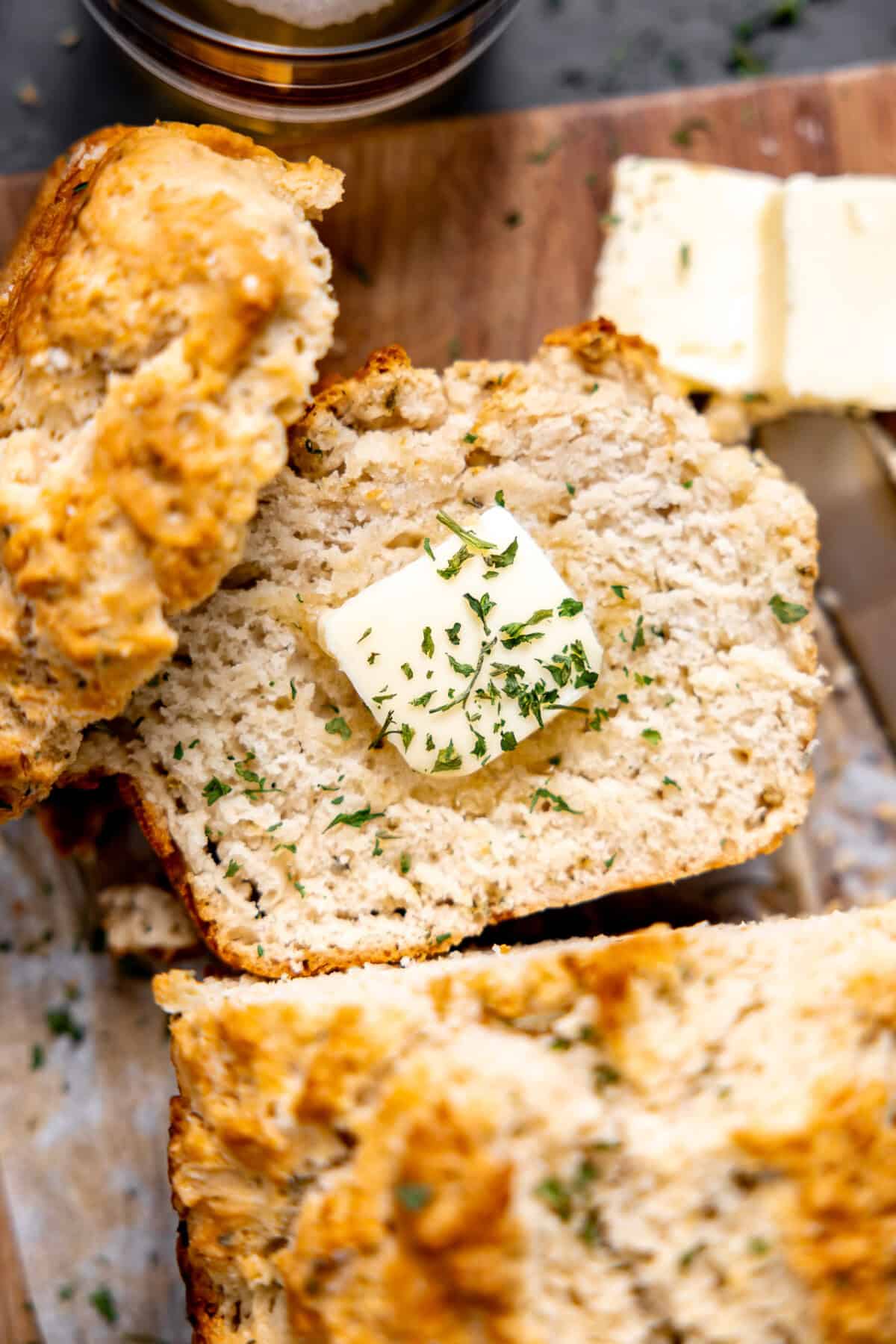 Sliced beer bread with butter and herbs on it.