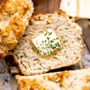 Sliced beer bread with butter and herbs on it.