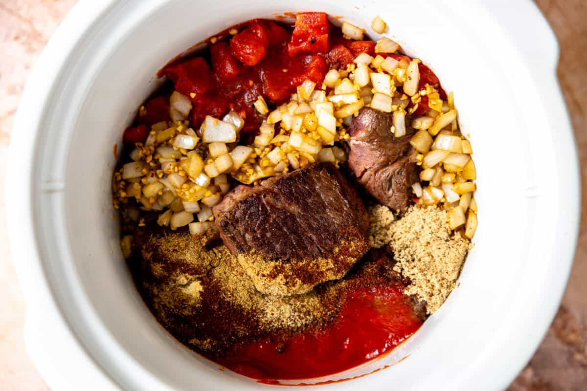 Ingredients needed to make chuck roast chili in a slow cooker before cooking. 