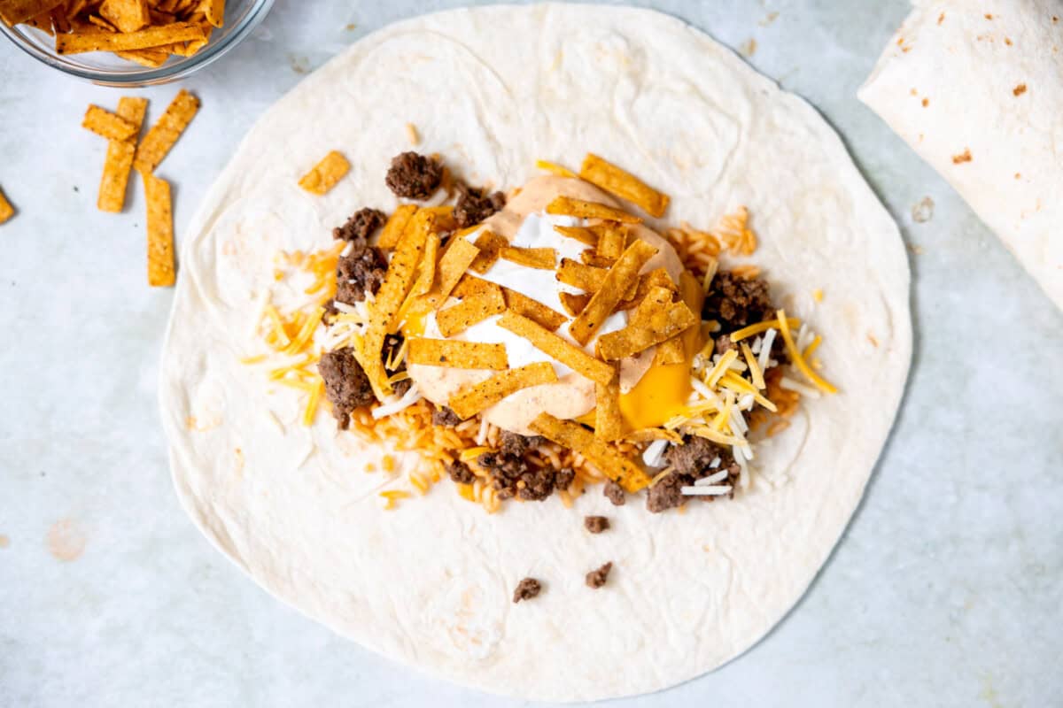 Adding filling to a tortilla to make a stuffed burrito.