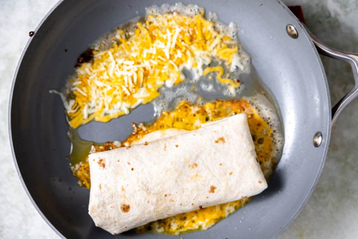 Grilling burrito in a skillet with melted cheese to stick to the tortilla. 