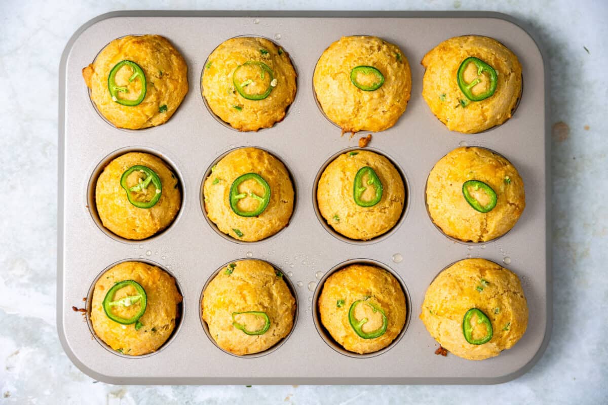 Baked Jalapeno Cornbread muffins each topped with a slice of jalapeno. 