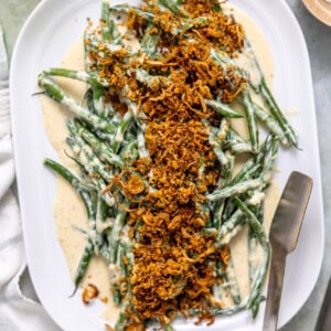 Creamed green beans on a white dish topped with a shallot herb crispy topping.