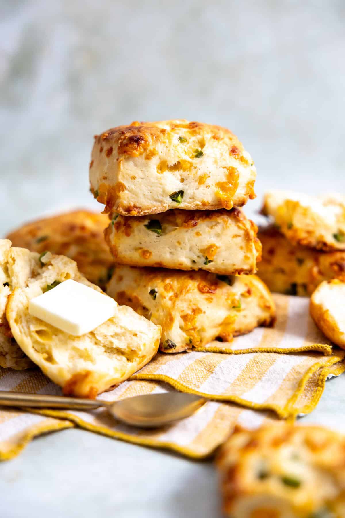 Stack of jalapeño cheddar biscuits with one split and butter spread on it. 