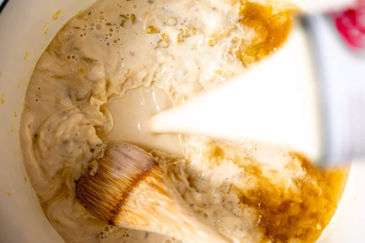 Pouring milk into a dutch oven to make creamy broccoli cheese soup. 