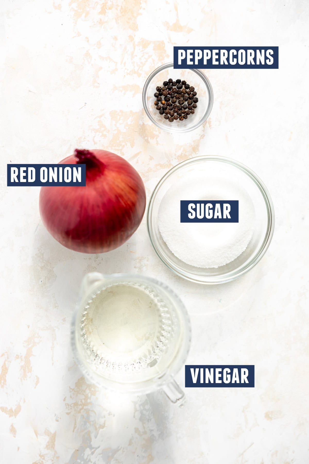 Ingredients needed to make pickled red onion including the red onion, peppercorns, sugar, and vinegar. 