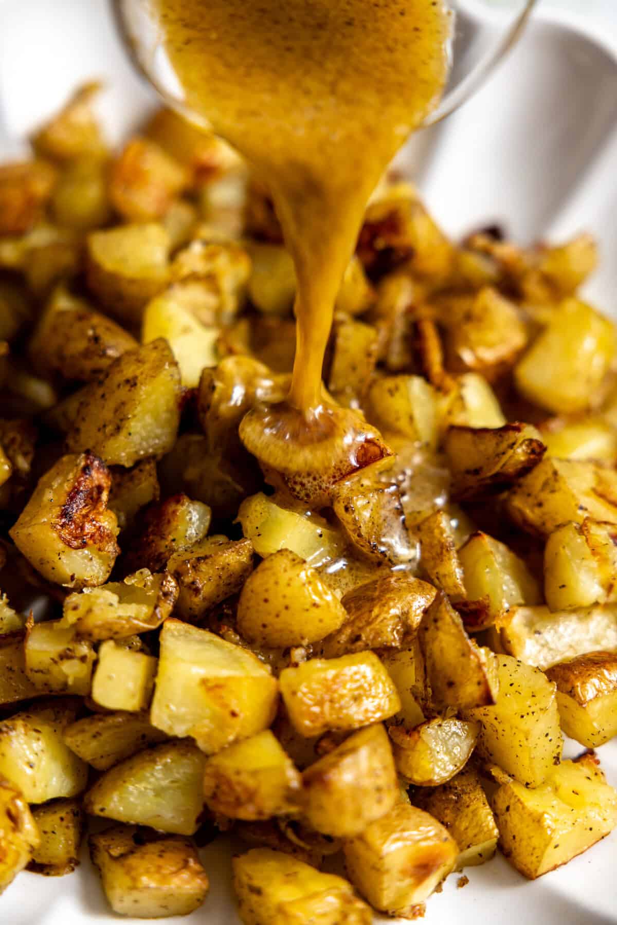 Pouring vinaigrette on top of roasted potatoes. 