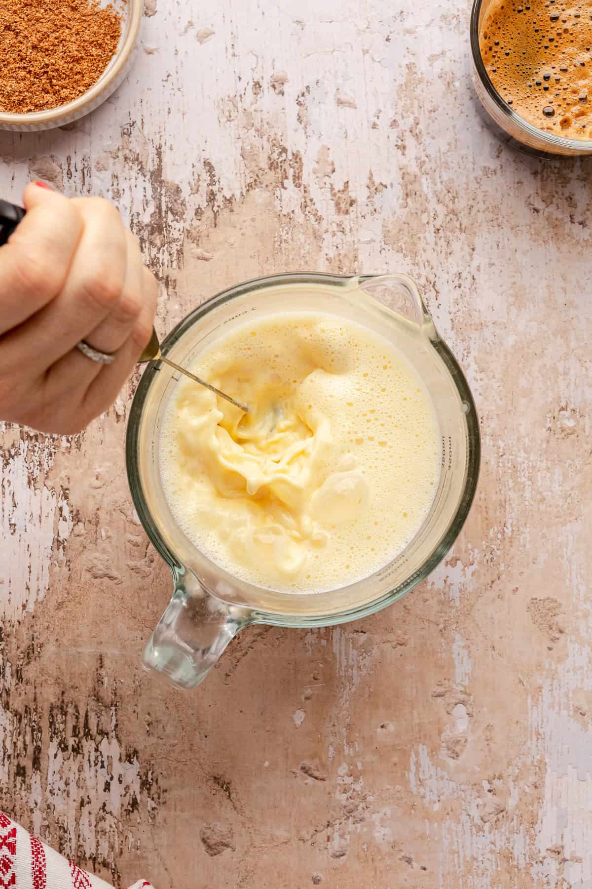 Frothing eggnog with a small whisk. 