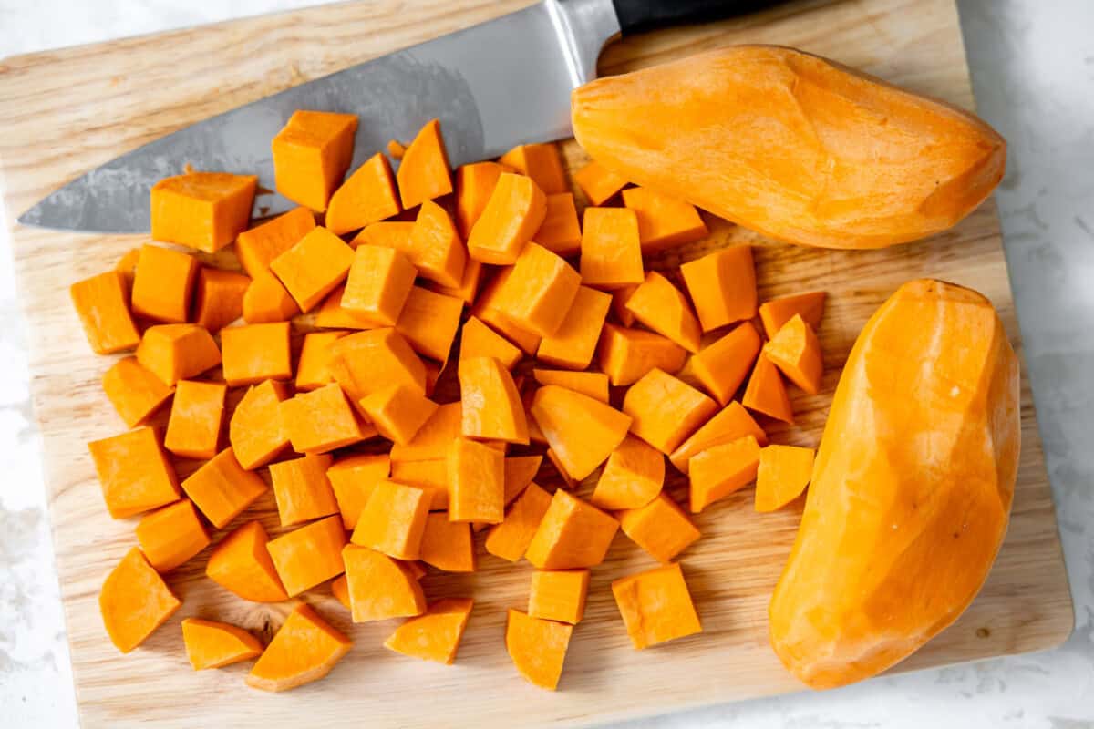 Chopping sweet potatoes on a wood cutting board. 