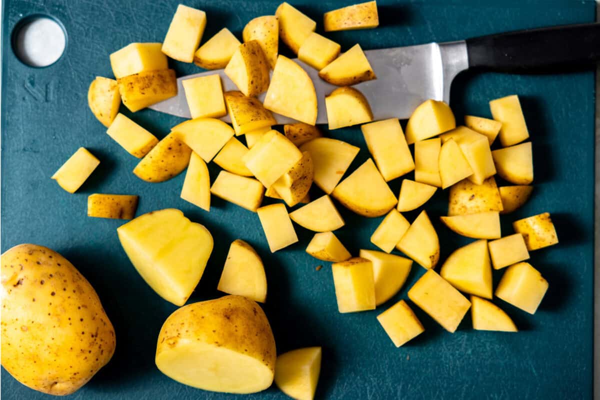 Chopped potato on a cutting board with a knife. 