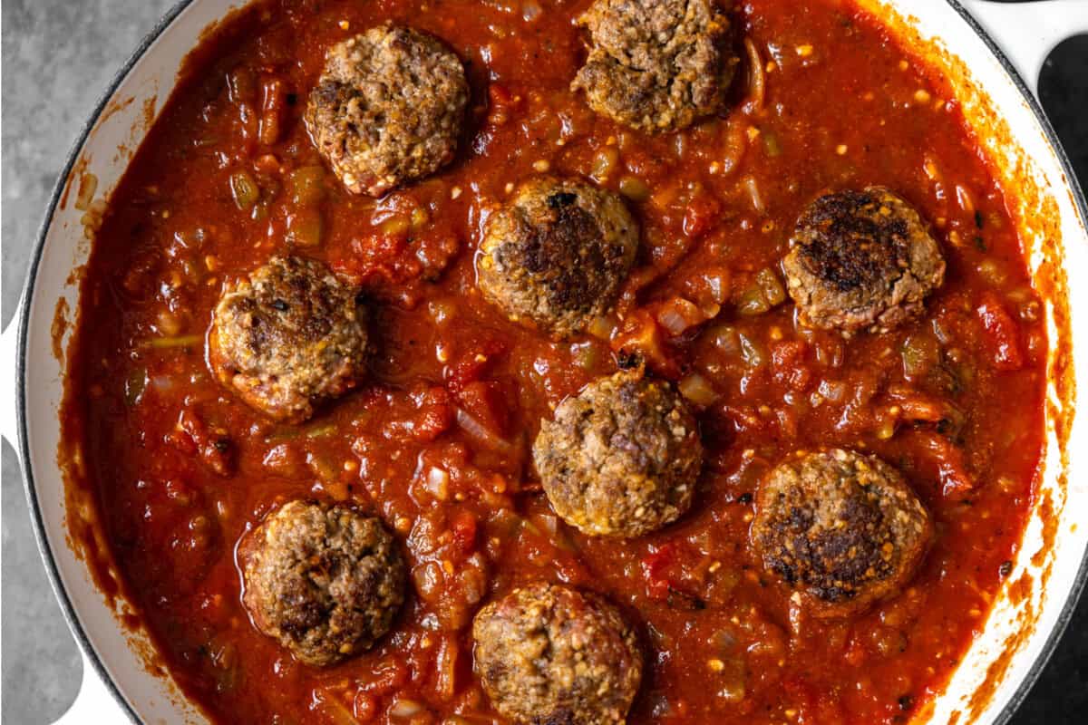 Adding meatballs into chili. 